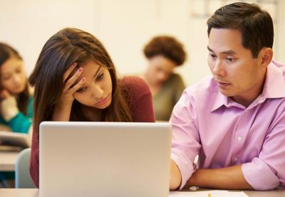 teacher helping stressed student with computer work
