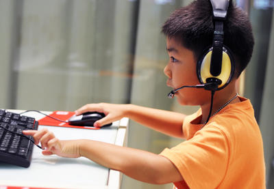 Boy uses computer with headphones on