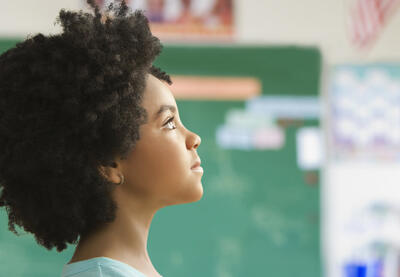 Girl, pictured from a side profile, looking up to focal point off camera