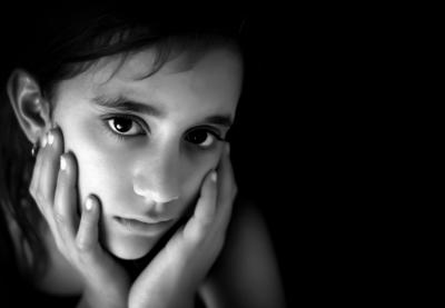 girl with face in hands looking sad in black and white