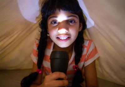 girl holding flashlight to her face