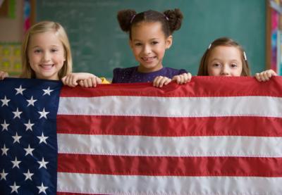 Three kids holding up American flag