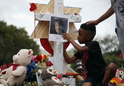 A young student writes a message on a makeshift memorial