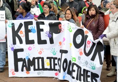 Immigrant families and allies gather behind a sign that reads, "Keep our families together."