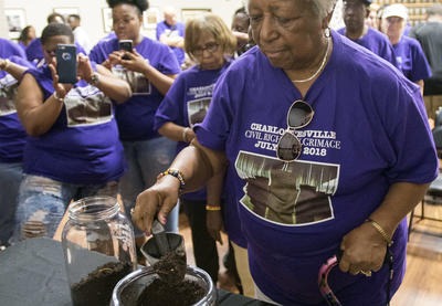 Woman on Charlottesville to Montgomery pilgrimage transfers soil from one jar to another