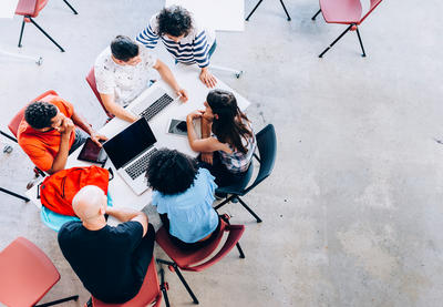 Group of students and teacher sitting around table having a discussion