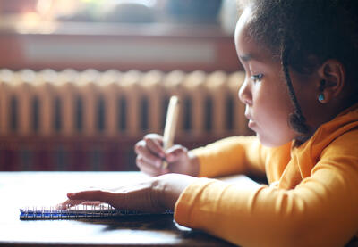 Young African-American girl writing in a notebook.