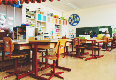 Group of students and teacher sitting near blackboard having a discussion.