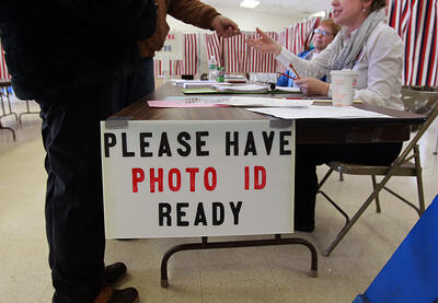 Voter handing photo identification to polling official.