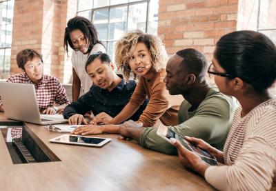 Group of professional led by woman of color gathered around documents.