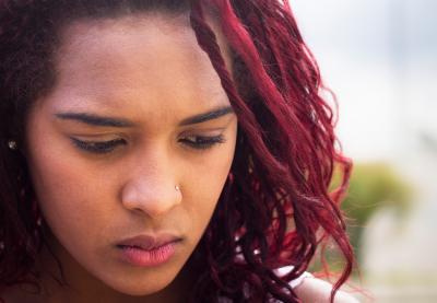 High school-aged student with red-colored hair looking downcast and pensive.