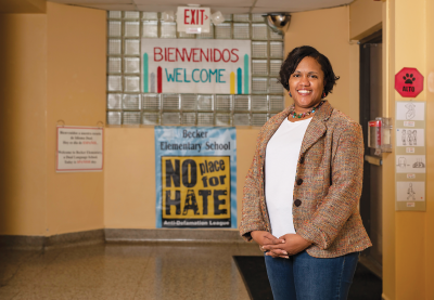 Angela Ward standing in a hallway with a variety of posters on the walls.