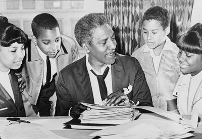 Civil rights and LGBTQ leader Bayard Rustin talking to four students gathered around him.