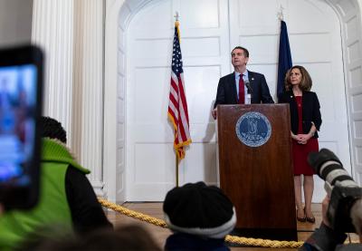 Ralph and Pam Northam behind a podium at a press conference.