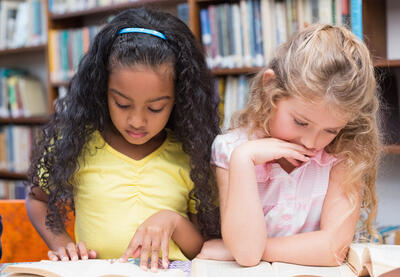 Two young students reading separate books.