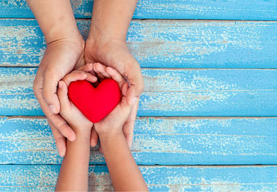 Hands hold a plush heart.