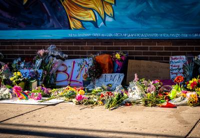 Signs with "Black Lives Matter" and "BLM" laid on the ground with flowers.