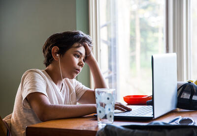 Young person sitting in front of a laptop computer.
