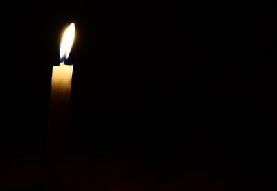 A single lit candle surrounded by darkness.