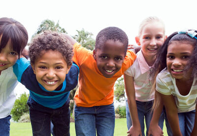 Five children leaning in toward the camera demonstrating community.