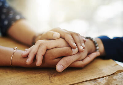 Two people hold hands in support of each other. 