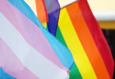 Transgender flag foreground and LGBTQ+ rainbow flag beside