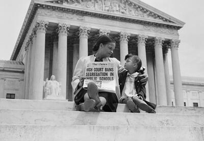 Image of woman and child on the steps of the Supreme Court with a newspaper with headline about the Brown decision
