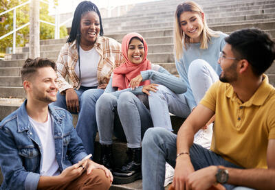Group of multiracial young people talking on steps