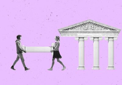 Two people carrying a column to a building