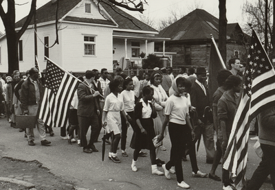Historical image of marchers with American flags participating in the 1965 Selma to Montgomery march