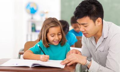 teacher helping student at her desk