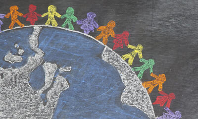 chalkboard drawing of multicolored stick people standing on globe