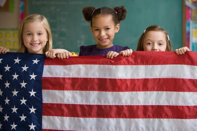 Three kids holding up American flag