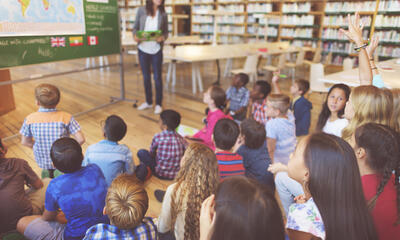 Young student raising hand to ask question during class lecture