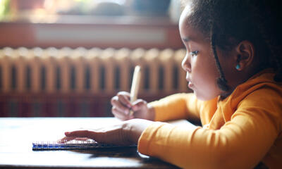 Young African-American girl writing in a notebook.