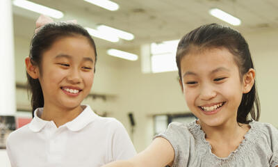 Two young Asian students smiling.