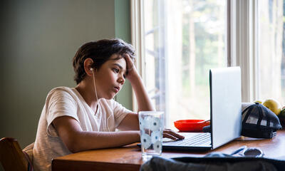 Young person sitting in front of a laptop computer.