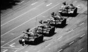 A black and white image of a man standing in front of a tank at Tiananmen Square.