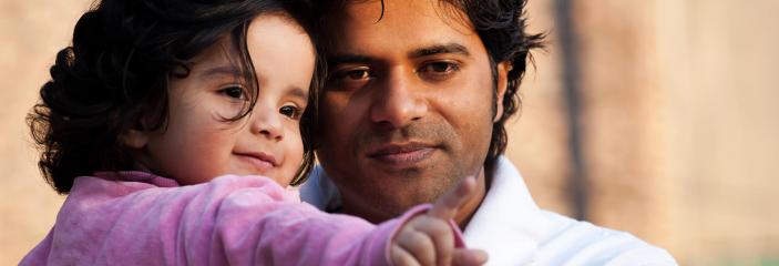 Father holding daughter and watching her pointing