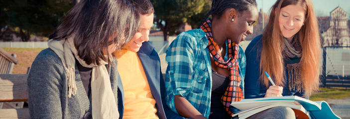 students looking over homework sitting on bench outside