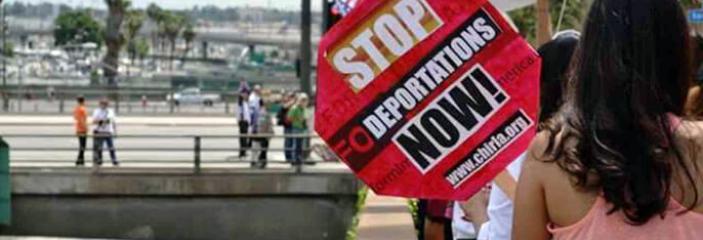 AFT link photo of protestor holding sign that says "Stop deportations now!"