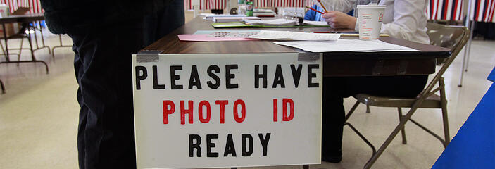 Voter handing photo identification to polling official.