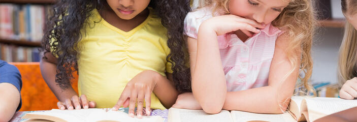 Two young students reading separate books.