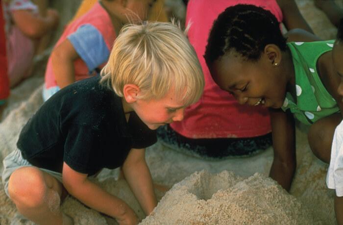 Different race kids playing together in the sand