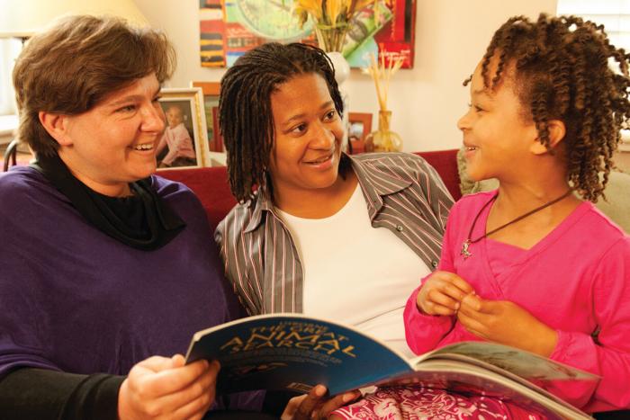 Adult couple with their daughter reading a book