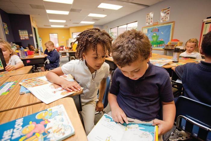 Students sharing a book in the classroom