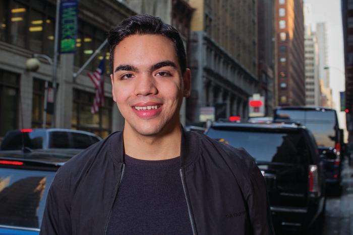 Pichardo stands in front of New York City scenery