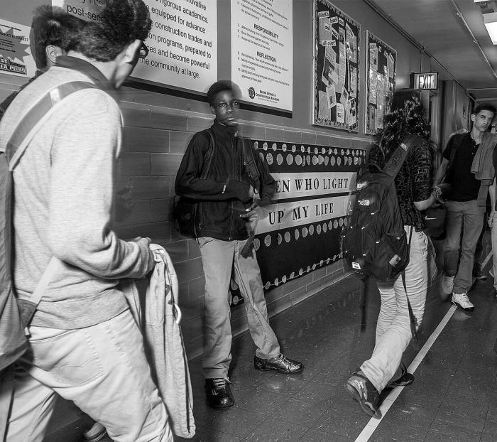 Teaching Tolerance photo of Black High School Students standing alone in the hall while others passing by