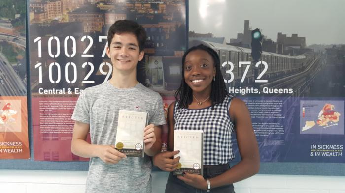 Two students holding copies of the book 'Evicted: Poverty and Profit in the American City.'