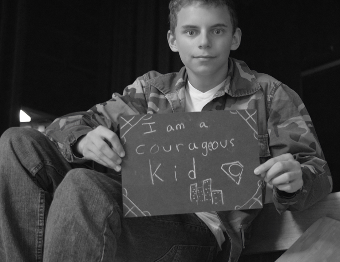 Young student holding sign that says "I am a courageous kid."